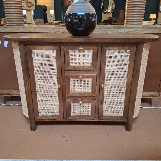 Wooden sideboard with wicker doors in a store setting