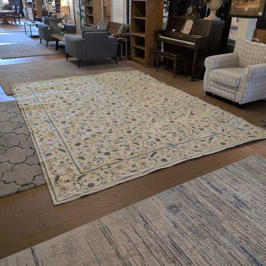 Floral patterned rug on a wooden floor with furniture in the background