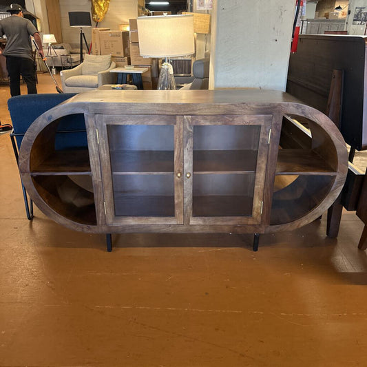 Wooden entertainment console with glass doors in a furniture store setting