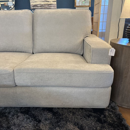 Gray sectional sofa in a room setting with a lamp and wall art.