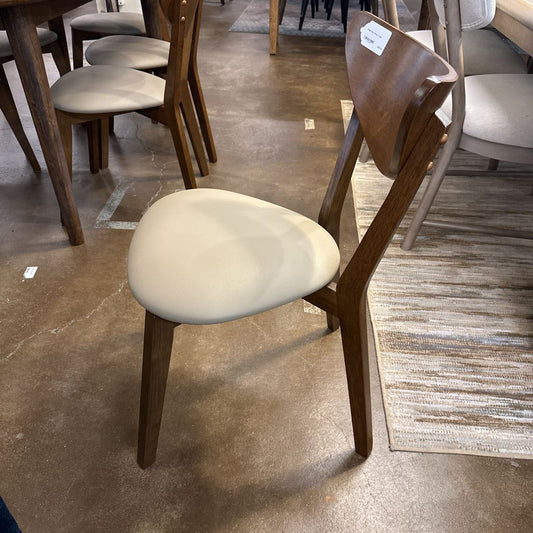 Wooden chair with a beige cushion on a floor with other furniture in the background