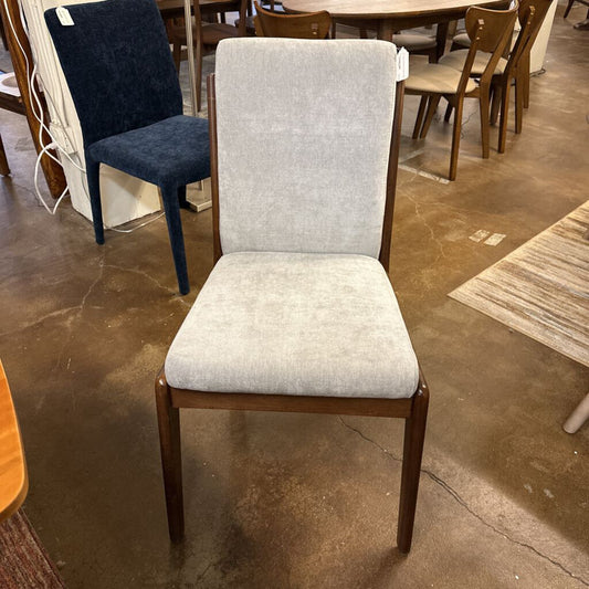 Gray upholstered chair with wooden frame on a concrete floor