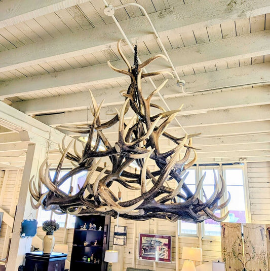 Antler chandelier hanging in a room with wooden walls and ceiling
