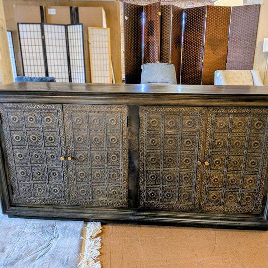 Decorative wooden cabinet with intricate patterns in a room setting.
