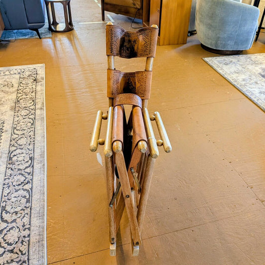 Wooden folding chair on a wooden floor with a rug and furniture in the background