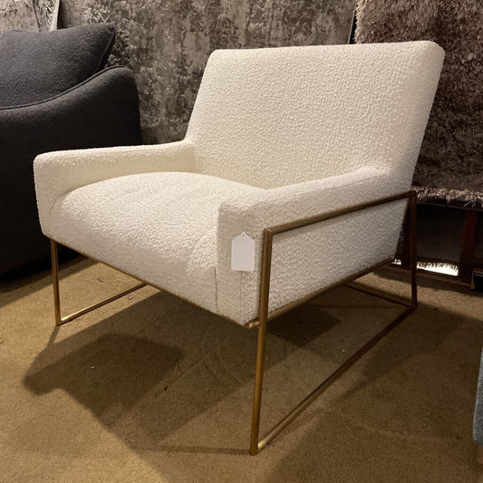 Contemporary accent chair upholstered in white bouclé fabric, featuring a square silhouette and thick armrests on a minimalist gold metal sled base.