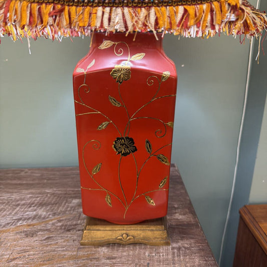 Decorative red lamp with gold floral patterns on a wooden surface.