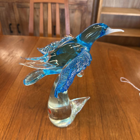 Glass sculpture of a fish with blue and clear colors on a wooden surface