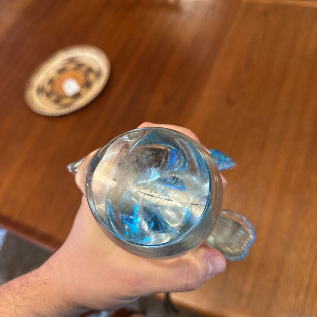 Hand holding a clear glass with metal rim against a wooden background