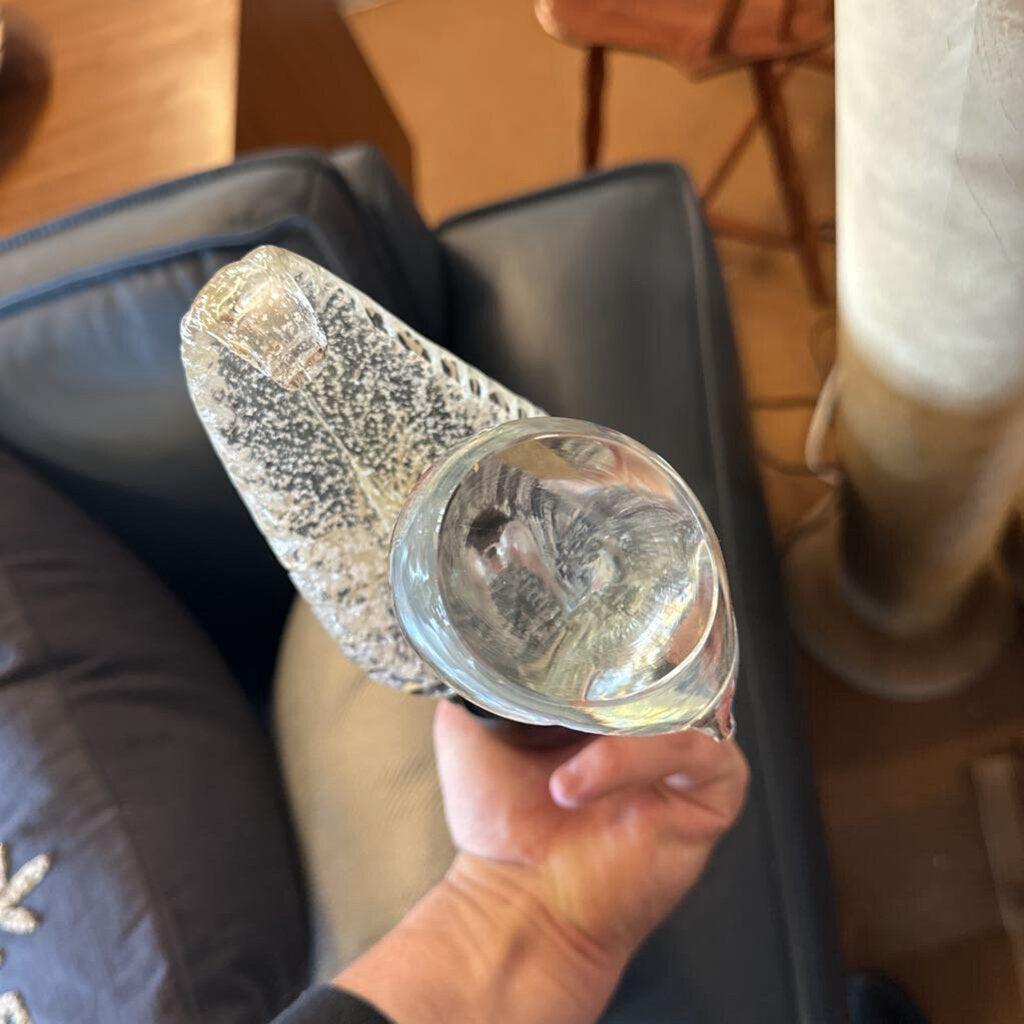 Hand holding a textured glass object with a blurred background