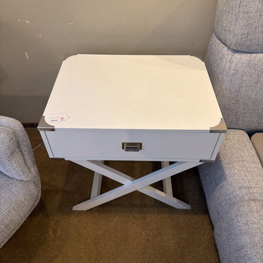 Small white table with a drawer in front of a gray sofa.
