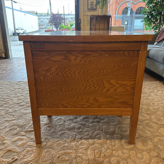 Wooden desk in a room with a textured carpet and a window in the background