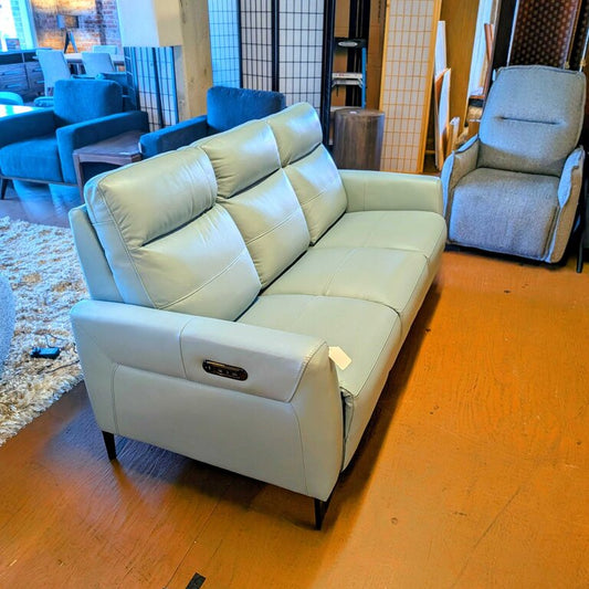 Light gray sofa in a room with wooden flooring and other furniture.