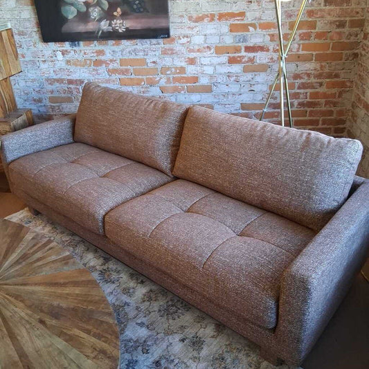 Brown sofa in a room with a brick wall and decorative rug.