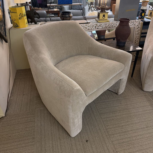 Beige armchair in a room with furniture and decor items.