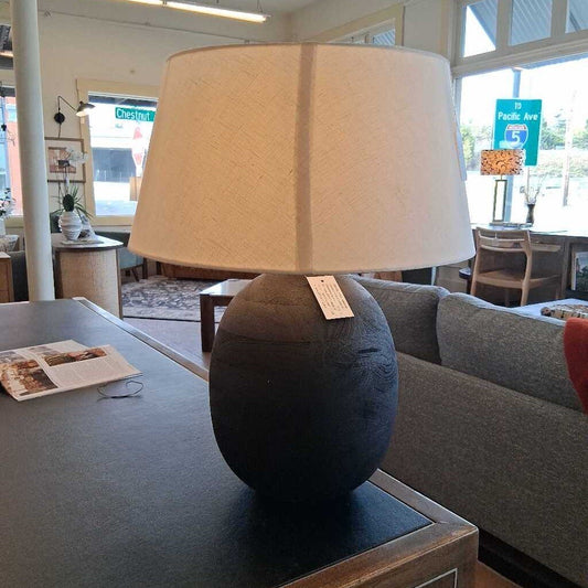 Table lamp with beige shade on a table in a room setting