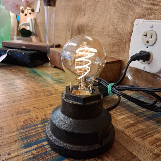 Light bulb on a wooden surface with a power outlet in the background