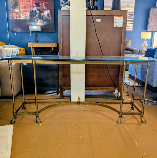 Glass table with gold legs in a room with blue walls and furniture.