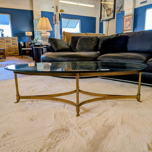 Living room with a black sofa, glass coffee table, and decorative items.