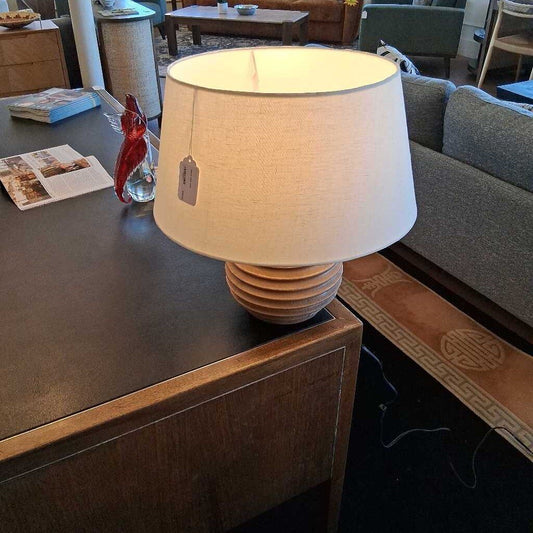 Lamp with a beige shade on a wooden table in a living room setting