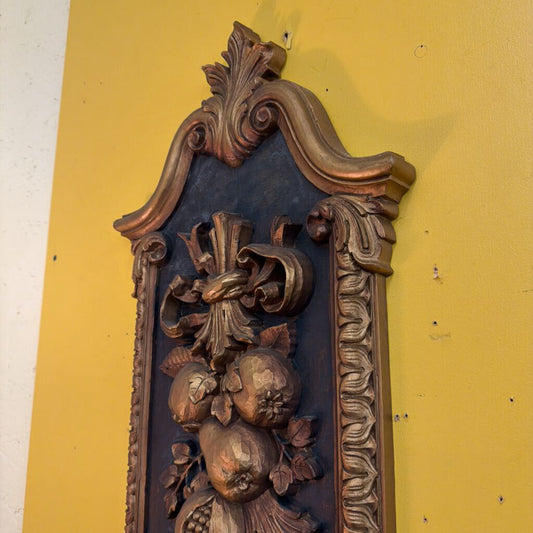 Decorative wooden panel with intricate carvings on a yellow wall.