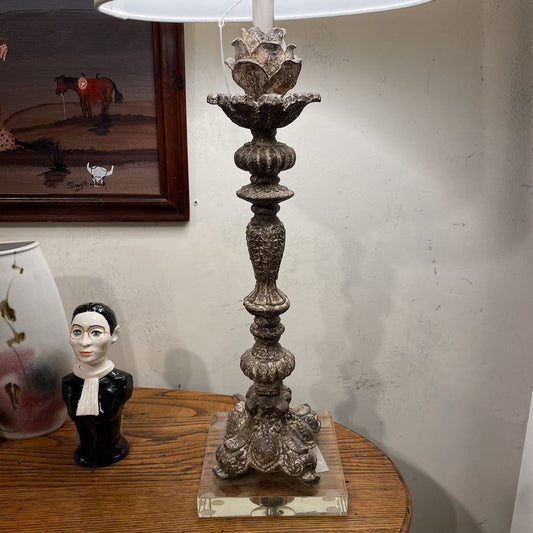 Decorative lamp with intricate design on a wooden surface, with a painting of a horse in the background.