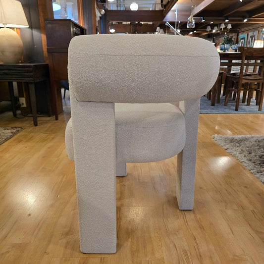 Gray upholstered chair on a wooden floor in a showroom setting