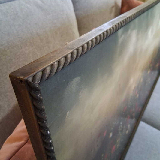 Wooden picture frame with a textured border held against a neutral background