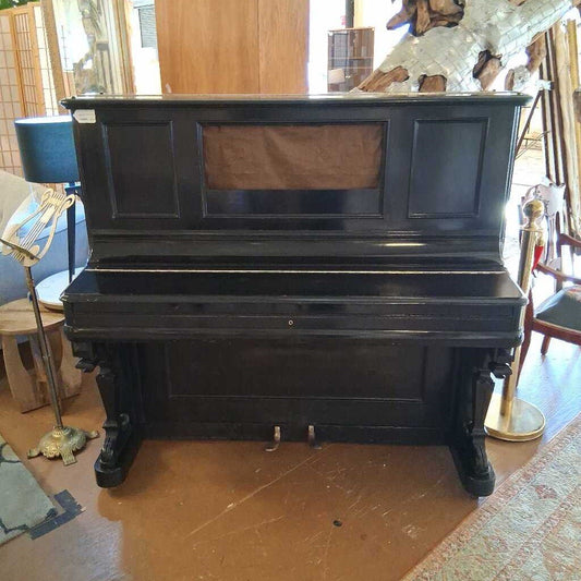 Black upright piano in a room with wooden floor and decorative elements