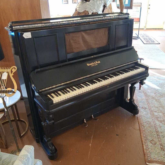 Black upright piano in a room with a rug and chair