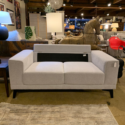 Gray sofa in a showroom with various decor items in the background