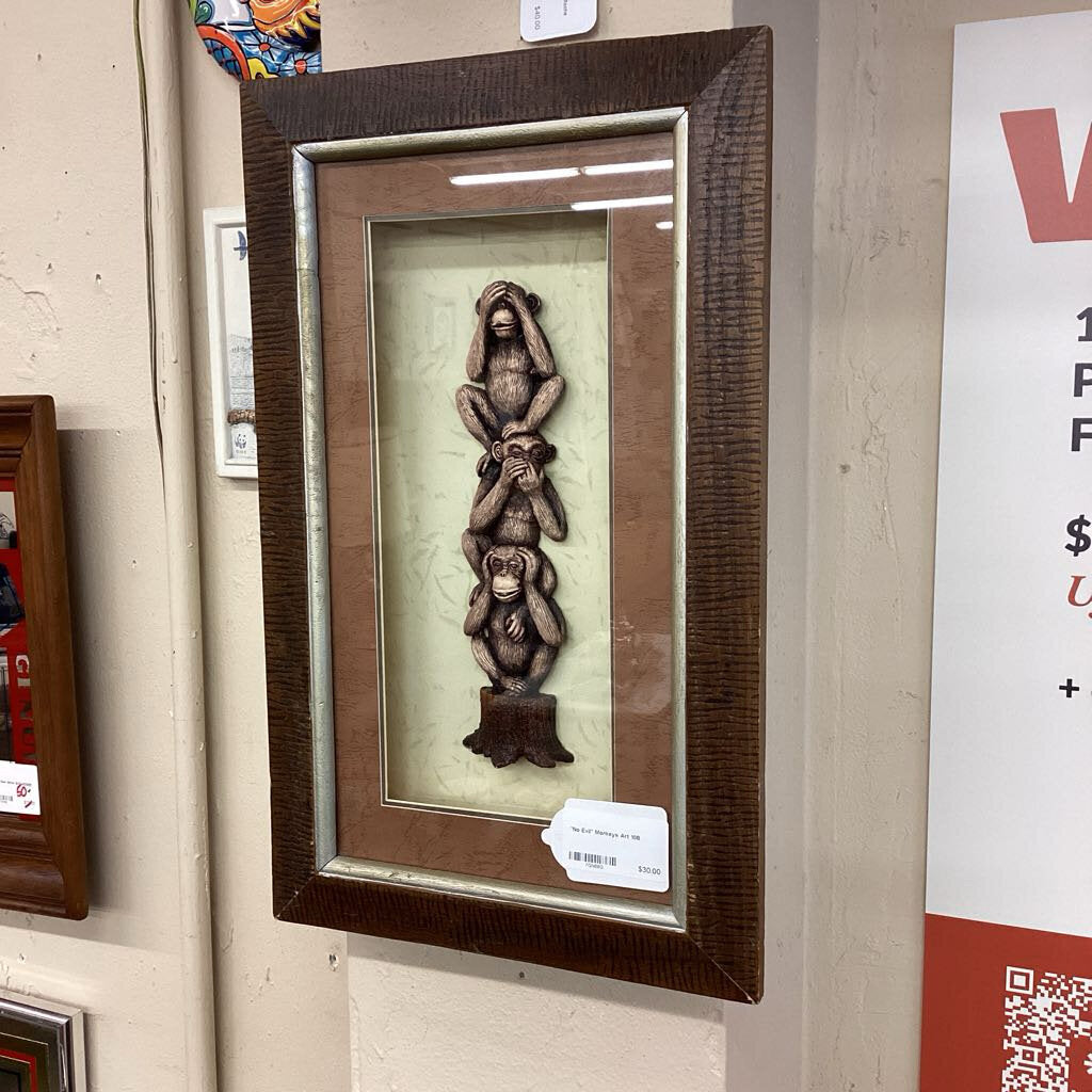 Framed artwork of three monkeys on a wall with a visible price tag.