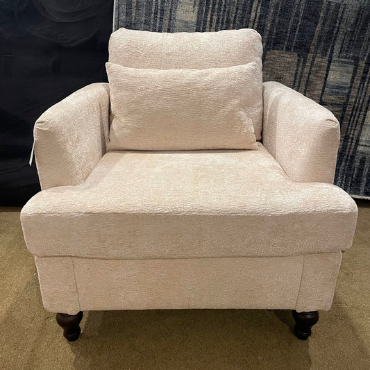 a beige soft textured armchair with a matching pillow and dark wooden spindle legs