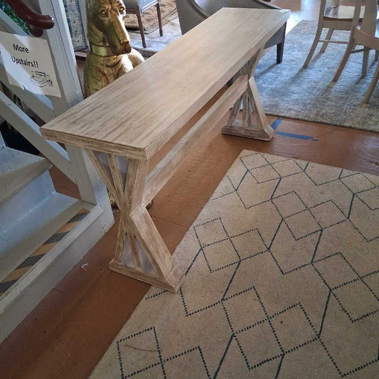 Wooden console table in a room with a patterned rug and furniture.