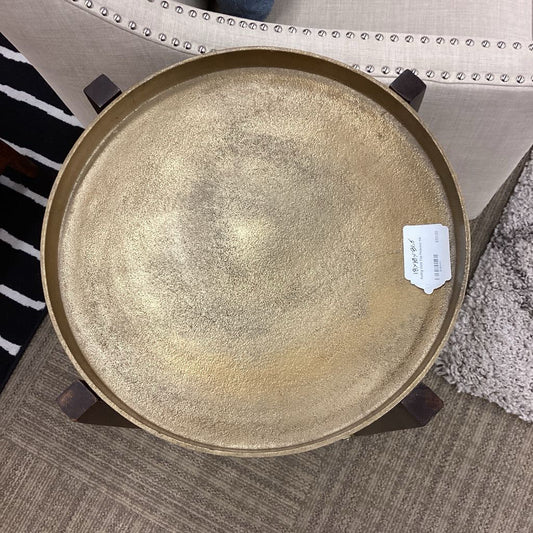 Round metallic tray on a textured surface with a label