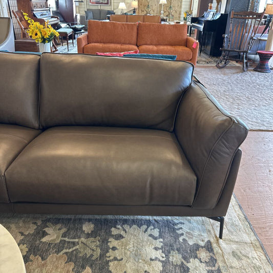 Brown leather sofa in a room with a rug and furniture.