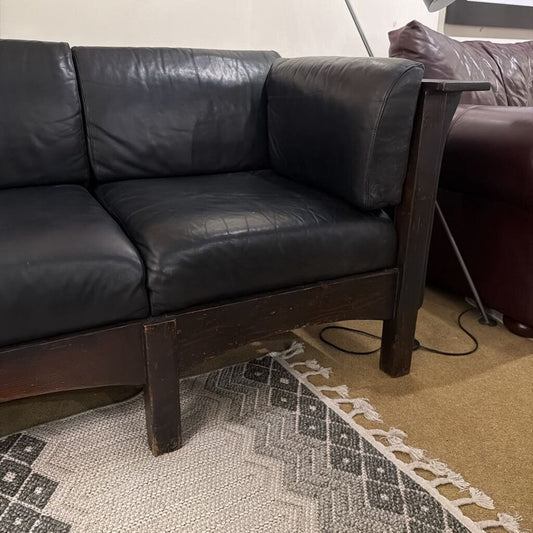 Black leather sofa with wooden legs on a patterned rug
