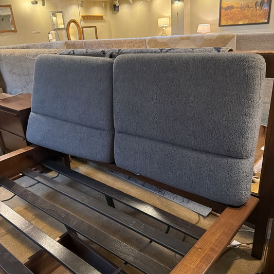 Gray upholstered bench with wooden frame in a showroom setting