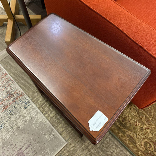 Wooden ottoman with a price tag on a patterned rug