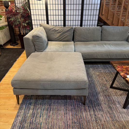 Gray sectional sofa with matching ottoman in a living room setting.