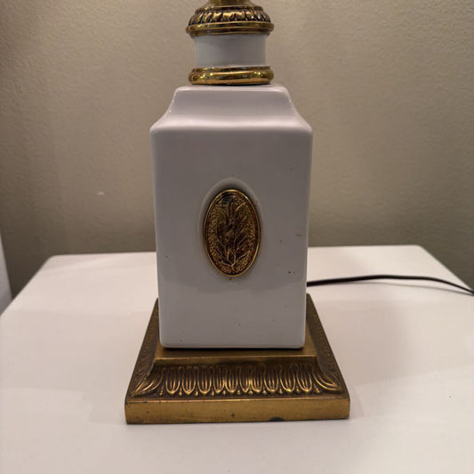 White lamp with gold decorative elements on a plain background