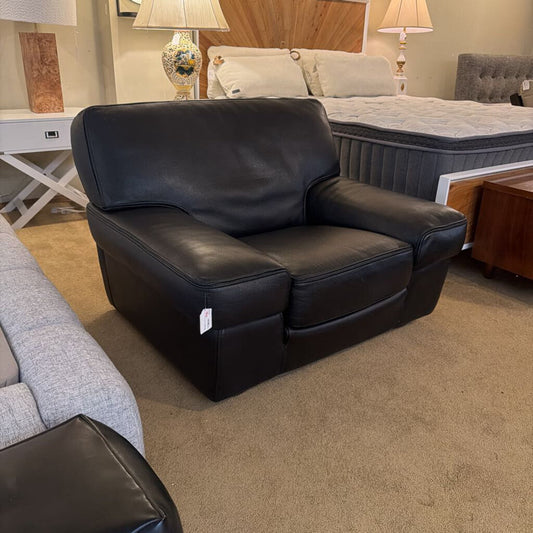 Black leather recliner chair in a room with furniture and decor.