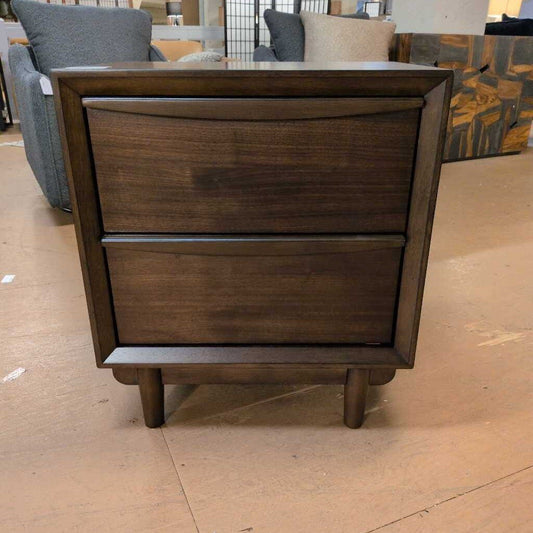 Wooden nightstand with two drawers on a wooden floor.