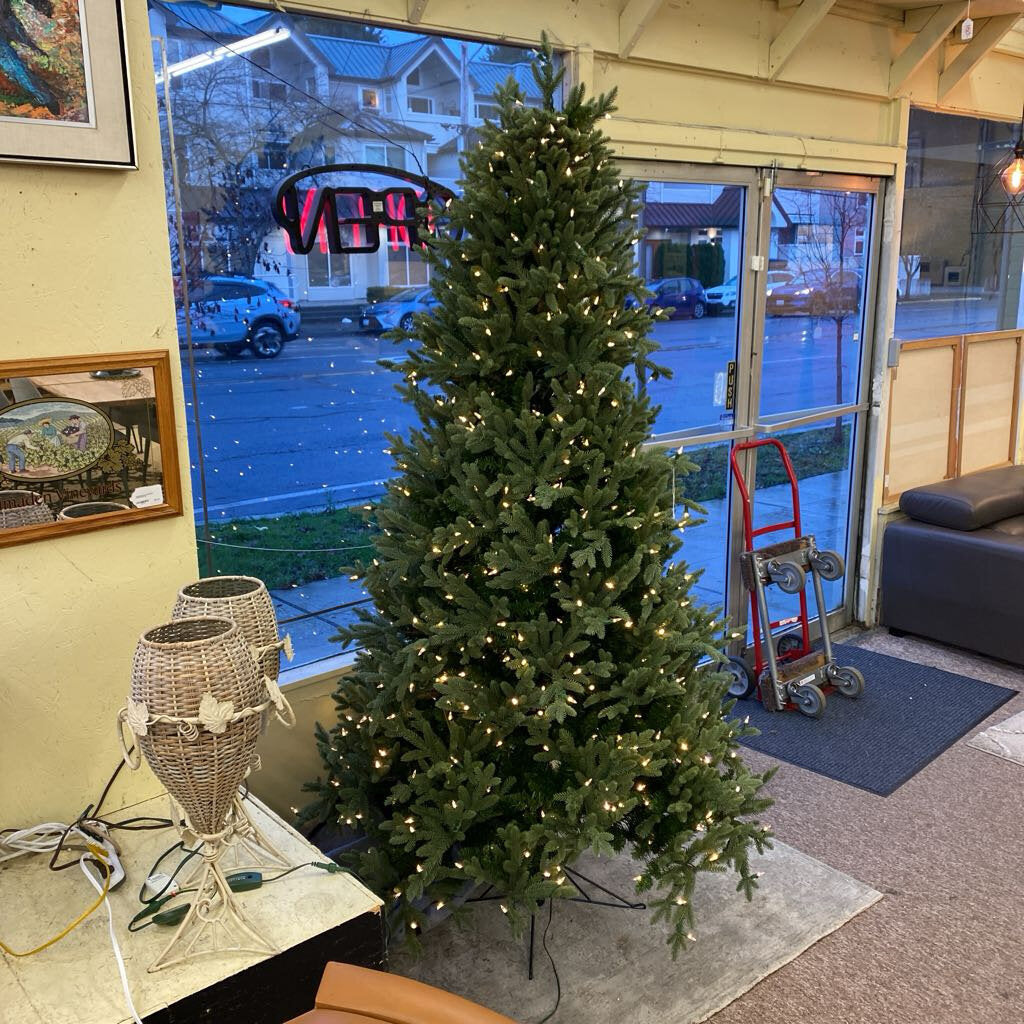 Decorative Christmas tree with lights in a room with a sliding glass door.