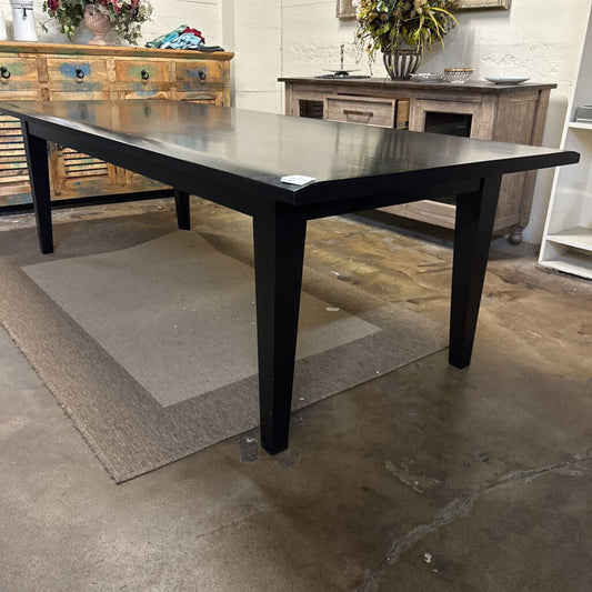 Black dining table in a room with wooden furniture and decorative items.