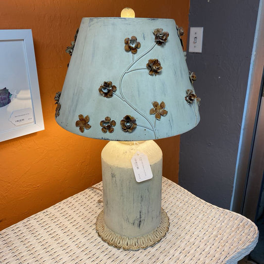 Decorative lamp with a floral design on a lampshade in a room setting.