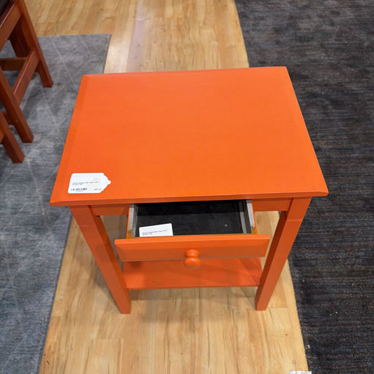 Orange side table with a drawer on a wooden floor