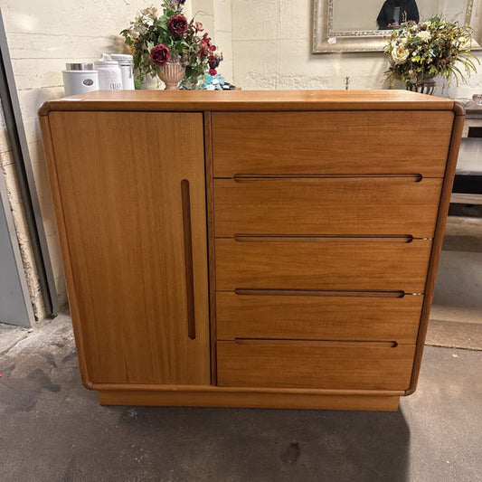 Wooden dresser with a door and drawers in a room setting.