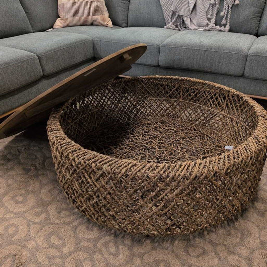 Round woven coffee table in front of a gray sectional sofa.