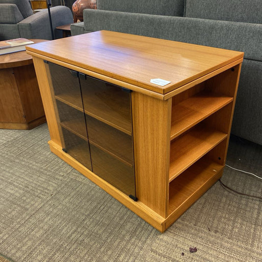 Wooden shelf with glass doors in a room with gray carpet and furniture.